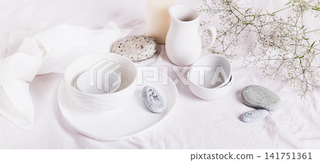 White ceramic dishes, white linen cloth, fabrics and dried flowers on the table web banner 141751361