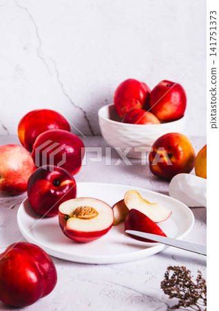 Fresh juicy nectarines, whole and sliced, on a plate on the table, top view Fresh juicy nectarines, whole and sliced, on a plate on the table, top view 141751373