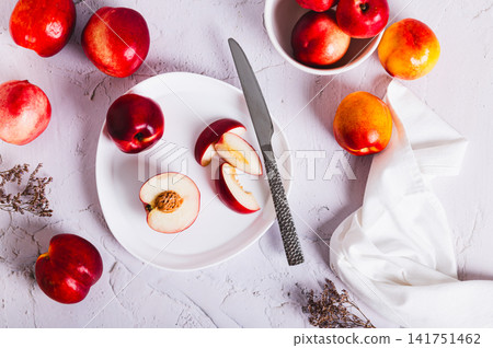 Fresh juicy nectarines, whole and sliced, on a plate on the table top view Fresh juicy nectarines, whole and sliced, on a plate on the table top view 141751462