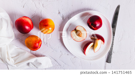 A plate with sliced sweet nectarines and a knife on the countertop is a kind of web banner A plate with sliced sweet nectarines and a knife on the countertop is a kind of web banner 141751465