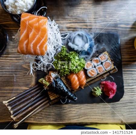 Artfully plated sushi assortment with smoked dry ice effect, fresh salmon, and elegant Japanese dining presentation Artfully plated sushi assortment with smoked dry ice effect, fresh salmon, and elegant Japanese dining presentation 141751524