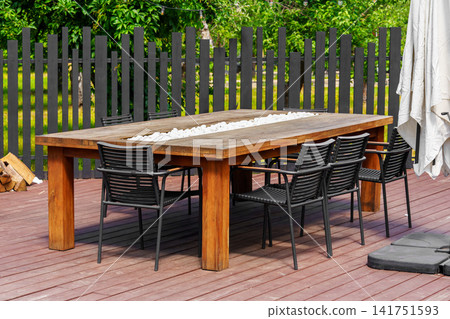 Modern outdoor dining table and chairs on backyard patio terrace, place to relax for group of people Modern outdoor dining table and chairs on backyard patio terrace, place to relax for group of people 141751593