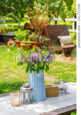 Rustic garden table setting with wildflower bouquet in summer backyard, patio relaxation area Rustic garden table setting with wildflower bouquet in summer backyard, patio relaxation area 141751599