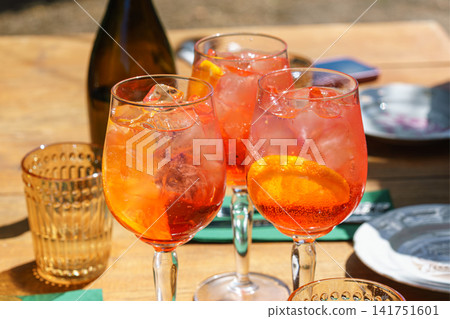 Three glasses or refreshing orange spritz cocktails with ice and citrus slices on sunny summer patio Three glasses or refreshing orange spritz cocktails with ice and citrus slices on sunny summer patio 141751601