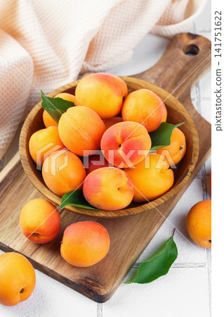 Fresh ripe apricots fruits in wooden bowl on white tile background. healthy eating, food ingredient Fresh ripe apricots fruits in wooden bowl on white tile background. healthy eating, food ingredient 141751622