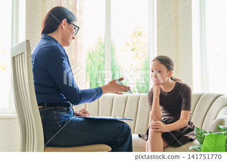Female psychologist talking to a young girl during a therapy consultation Female psychologist talking to a young girl during a therapy consultation 141751770
