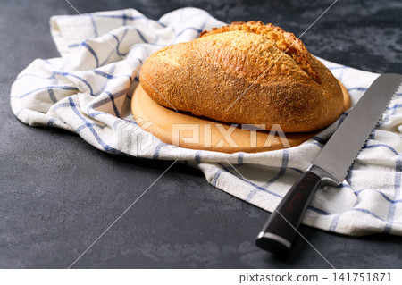 Artisan bread or traditional wheat rustic bread on dark kitchen table, selective focus. Artisan bread or traditional wheat rustic bread on dark kitchen table, selective focus. 141751871