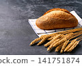 loaf of wheat bread with sourdough with ears of wheat on dark kitchen table, selective focus 141751874