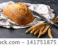 Crusty loaf of sourdough bread with ears of wheat on dark kitchen table, selective focus. 141751875