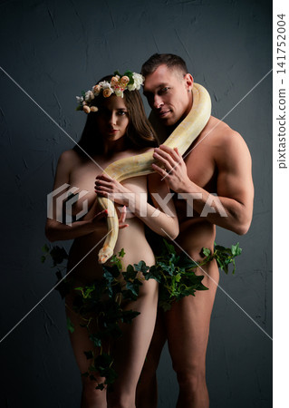 Nude couple with floral crown and yellow snake against dark textured backdrop Nude couple with floral crown and yellow snake against dark textured backdrop 141752004