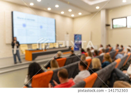 Blurred background of business conference with audience seated in auditorium Blurred background of business conference with audience seated in auditorium 141752303