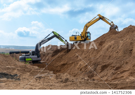 Two excavators operating on a construction site Two excavators operating on a construction site 141752306