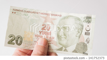 A hand holding a twenty Turkish Lira banknote flat against a white background. A hand holding a twenty Turkish Lira banknote flat against a white background. 141752373
