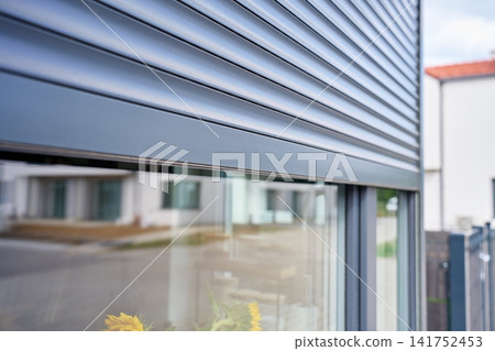Exterior roller shutter is lowered over the upper part of modern residential window Exterior roller shutter is lowered over the upper part of modern residential window 141752453