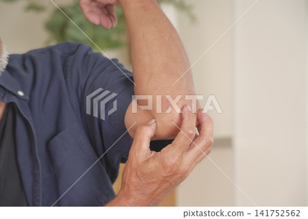 A middle-aged man winces in pain from elbow pain. A middle-aged man winces in pain from elbow pain. 141752562