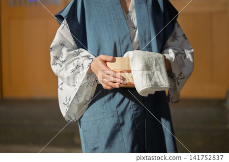 A woman wearing a yukata heading to a hot spring. A woman wearing a yukata heading to a hot spring. 141752837