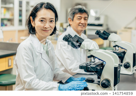 在實驗室中使用顯微鏡進行研究的研究人員 在實驗室中使用顯微鏡進行研究的研究人員 141754859