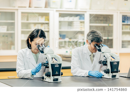 在實驗室中使用顯微鏡進行研究的研究人員 在實驗室中使用顯微鏡進行研究的研究人員 141754860