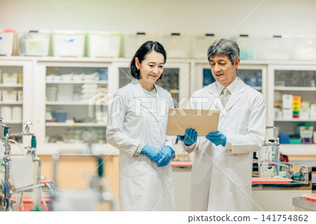在實驗室中使用顯微鏡進行研究的研究人員 在實驗室中使用顯微鏡進行研究的研究人員 141754862