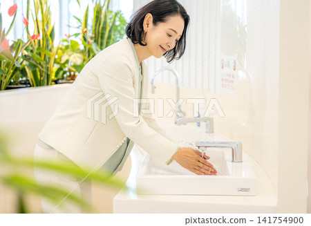 一位五十多歲的女商人正在辦公室洗手。 一位五十多歲的女商人正在辦公室洗手。 141754900