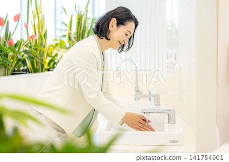 A businesswoman in her 50s washing her hands in the office. A businesswoman in her 50s washing her hands in the office. 141754901