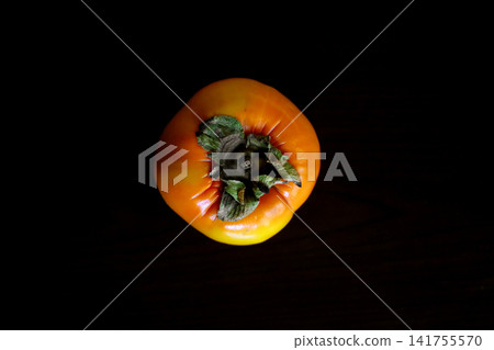 A bird's-eye view of a fully ripened persimmon placed against a black background. 141755570