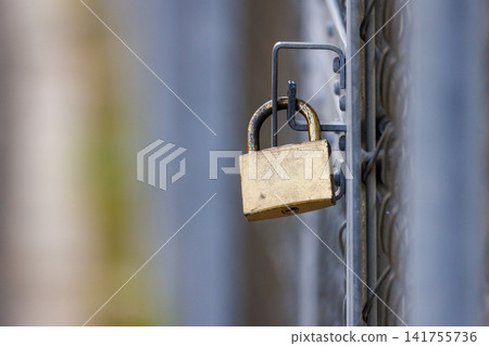 An old brass padlock attached to the fence An old brass padlock attached to the fence 141755736