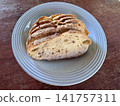 Fresh sliced artisan sourdough bread loaf on a blue ceramic plate over a rustic wooden table 141757311