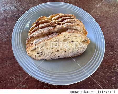 Fresh sliced artisan sourdough bread loaf on a blue ceramic plate over a rustic wooden table Fresh sliced artisan sourdough bread loaf on a blue ceramic plate over a rustic wooden table 141757311