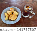 Close up view of delicious fresh peeled jackfruit in a blue ceramic plate with iced black coffee on a rustic wooden table 141757507