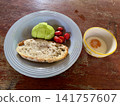 Close up view of delicious rustic sourdough toast with fresh avocado and cherry tomatoes on a wooden table 141757607