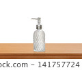 A clear glass perfume bottle with a diamond pattern on a wooden table. 141757724