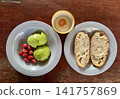 Close up view of delicious rustic sourdough toast with fresh avocado, cherry tomatoes and egg on a wooden table 141757869