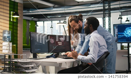 Programmer in office requesting help from coworkers to fix critical error warning. IT employee and colleagues brainstorming how to fix computer bug affecting systems, camera A Programmer in office requesting help from coworkers to fix critical error warning. IT employee and colleagues brainstorming how to fix computer bug affecting systems, camera A 141758394