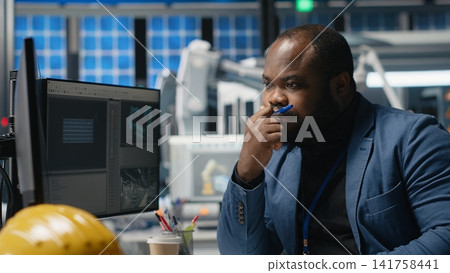 African american master engineer reviews operations in a solar tech plant, ensuring factory activity to meet green energy targets. Specialist uses tablet for manufacturing efficiency. Camera B. African american master engineer reviews operations in a solar tech plant, ensuring factory activity to meet green energy targets. Specialist uses tablet for manufacturing efficiency. Camera B. 141758441