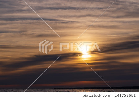 Golden sunset casts warm light across a calm sea Golden sunset casts warm light across a calm sea 141758691