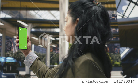 Green screen mobile phone used by tourist in bus station checking itinerary details ahead of departure. Woman reviews shuttle journey on chroma key smartphone while waiting, close up Green screen mobile phone used by tourist in bus station checking itinerary details ahead of departure. Woman reviews shuttle journey on chroma key smartphone while waiting, close up 141759014