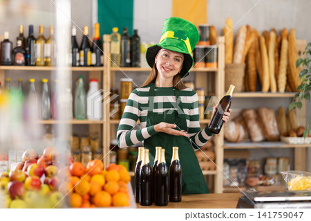 Positive friendly girl seller in traditional green Irish cap offers to buy Irish ale for St. Patrick Day celebration Positive friendly girl seller in traditional green Irish cap offers to buy Irish ale for St. Patrick Day celebration 141759047