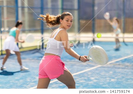 Woman standing on court and hitting ball with racket Woman standing on court and hitting ball with racket 141759174