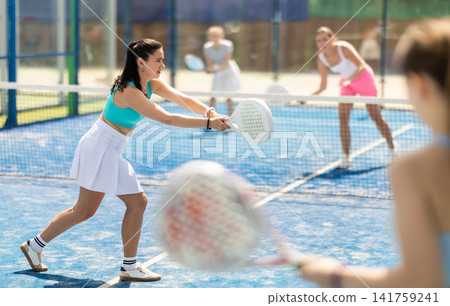 Adult woman plays paddle tennis against team of women Adult woman plays paddle tennis against team of women 141759241