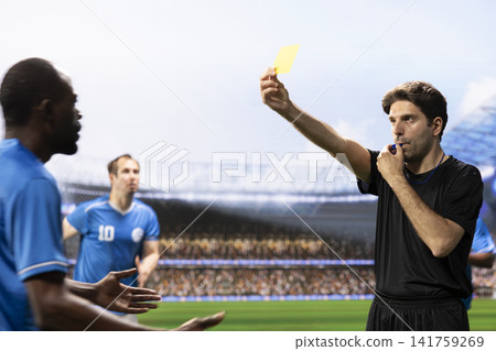 Referee in black uniform showing yellow card and blowing whistle, sanctioning rule violation with card warning. Blue team players protesting referee decision, foul and argument. Referee in black uniform showing yellow card and blowing whistle, sanctioning rule violation with card warning. Blue team players protesting referee decision, foul and argument. 141759269