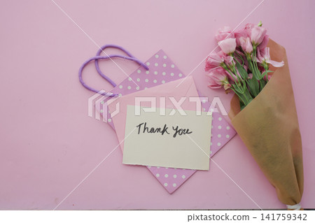Gift bag with flowers and thank you card on a pink surface 141759342