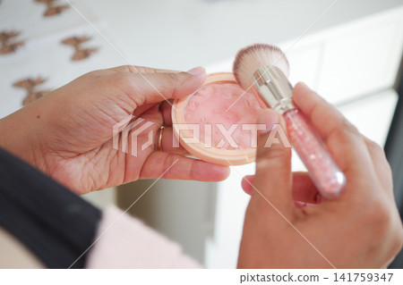 Applying blush with brush in a bright room Applying blush with brush in a bright room 141759347