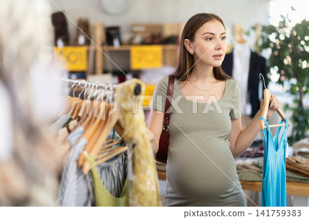 Pregnant woman choosing clothes Pregnant woman choosing clothes 141759383