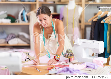 dressmaker marks and cuts the fabric dressmaker marks and cuts the fabric 141759422