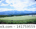A vast plateau landscape with majestic mountain ranges and a clear blue sky. 141759559