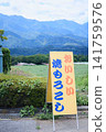 A sign advertising "delicious grilled corn" stands against a backdrop of majestic mountains. 141759576
