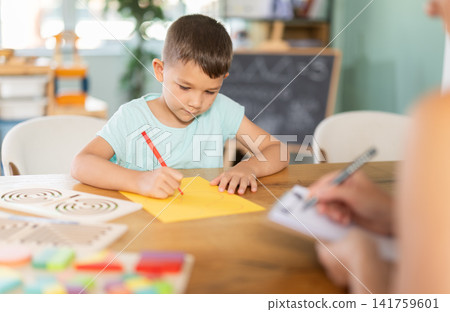 Boy draws or pass round geometric shapes on yellow sheet with pencil Boy draws or pass round geometric shapes on yellow sheet with pencil 141759601
