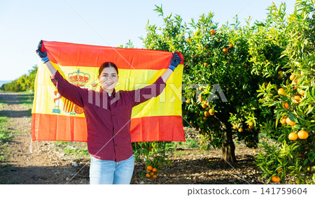 Girl football fan waving Spanish flag during tangerines harvest Girl football fan waving Spanish flag during tangerines harvest 141759604