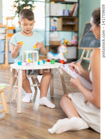 Boy plays with wooden sorter Boy plays with wooden sorter 141759609